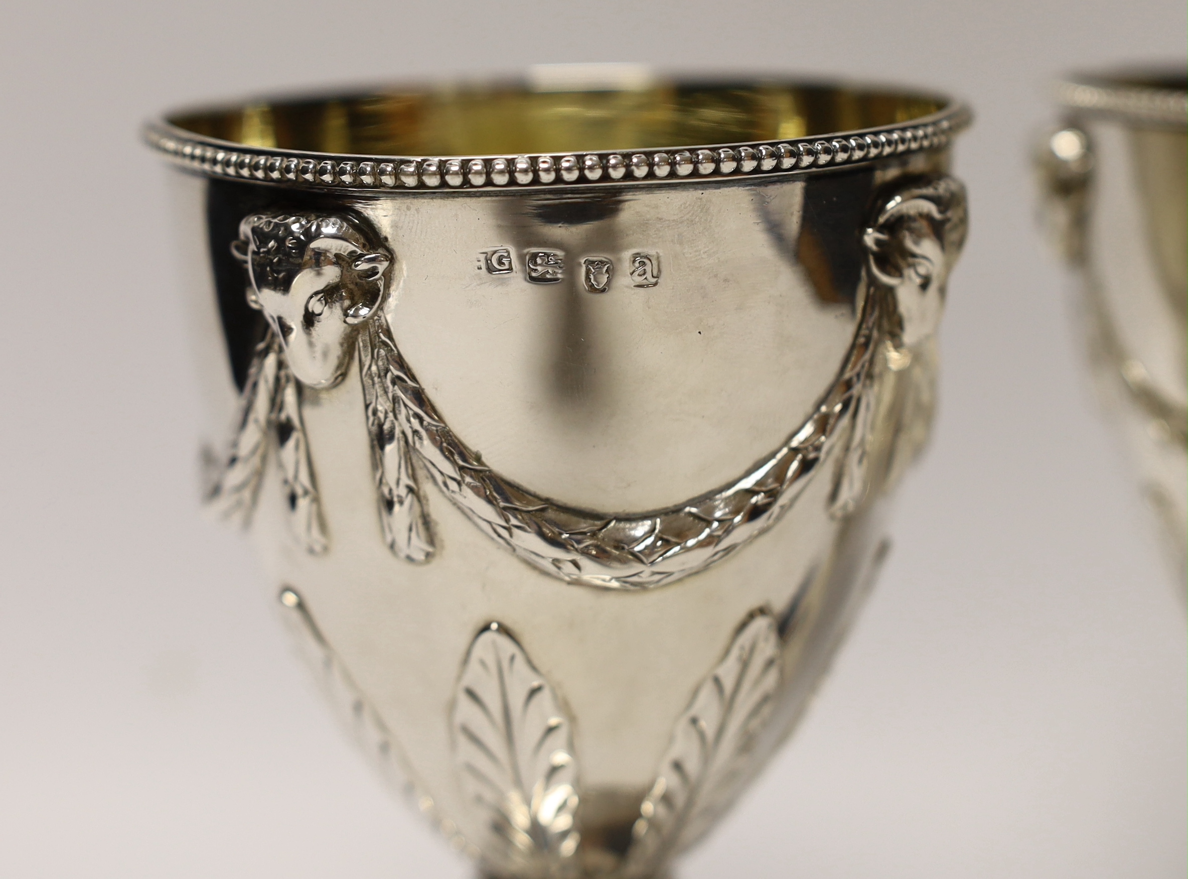 A pair of late George III silver goblets, with ram's head and swag decoration, maker H.G, London, 1816, 15.1cm, 16.3oz, with partly erased engraved inscriptions.